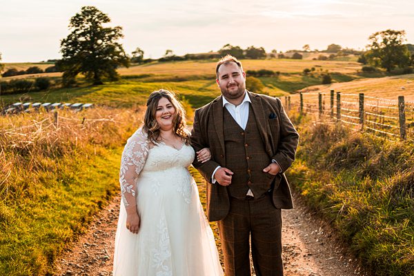 Couple poses in countryside during golden hour.