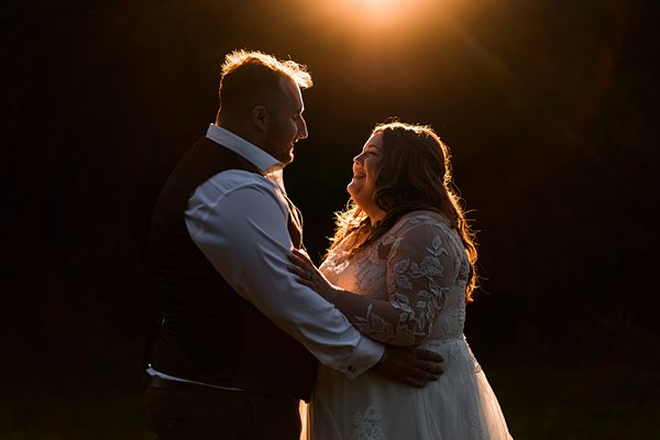 Sunset wedding couple embracing, smiling lovingly.