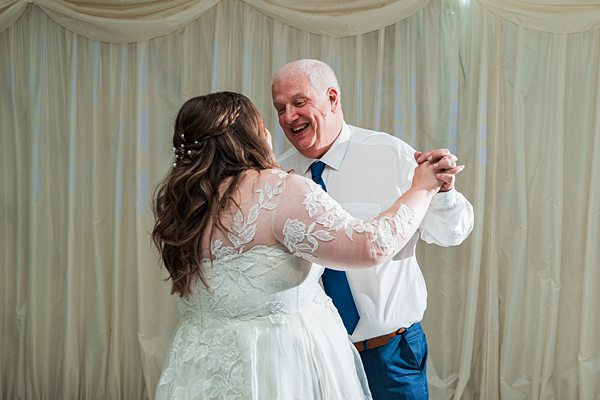 Bride and man dancing joyfully at wedding.