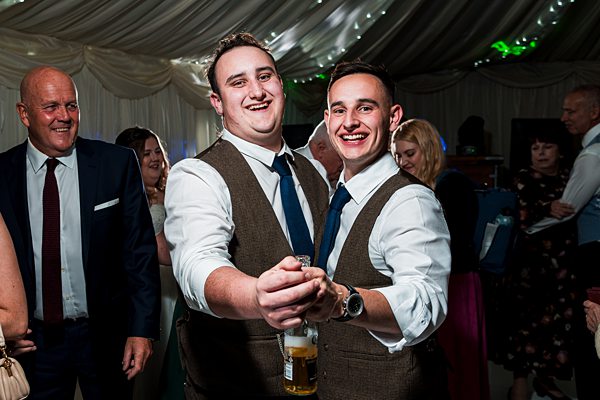 Two men smiling at a wedding reception.