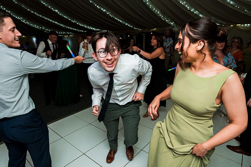 People dancing energetically at a lively wedding party.