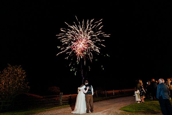 Wedding couple watching fireworks display at night.