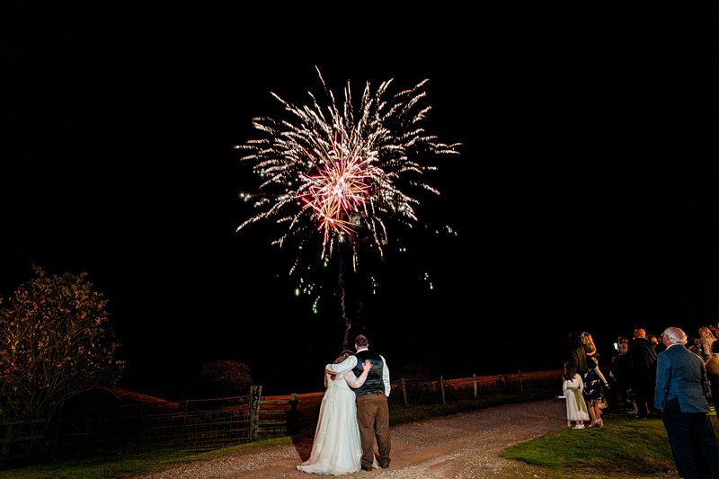 Wedding couple watching fireworks at night ceremony.
