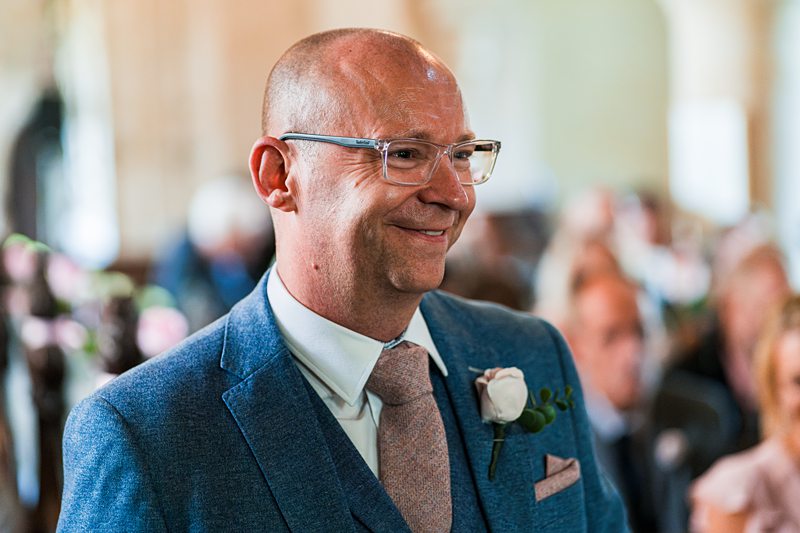 Smiling man in suit with boutonniere at event.