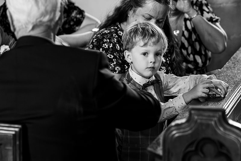 Child in suit at church ceremony, black and white.