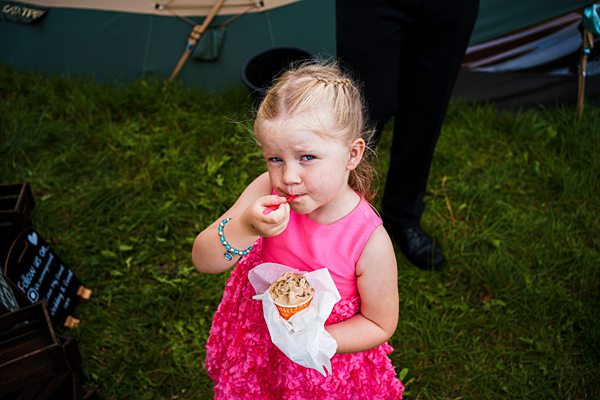 Young girl eating ice cream at outdoor event.