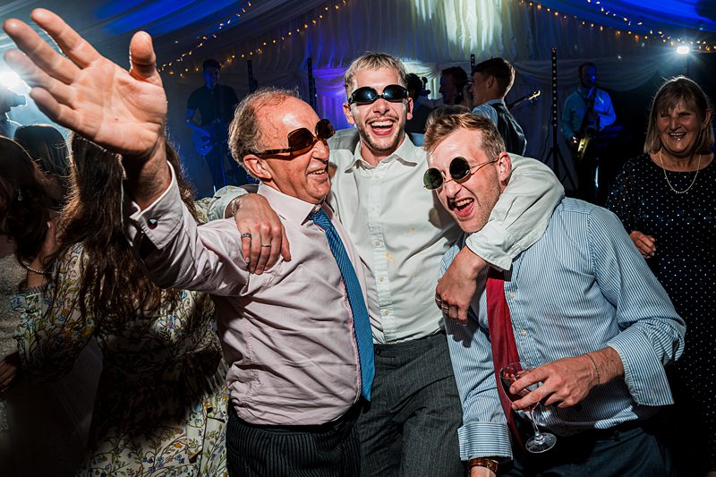 Three men in sunglasses celebrating at a party.
