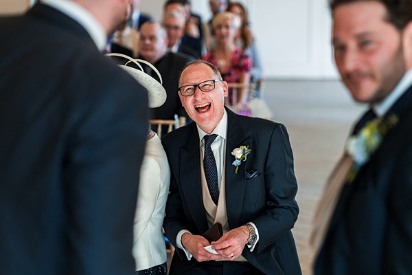 Man laughing at wedding ceremony, guests seated