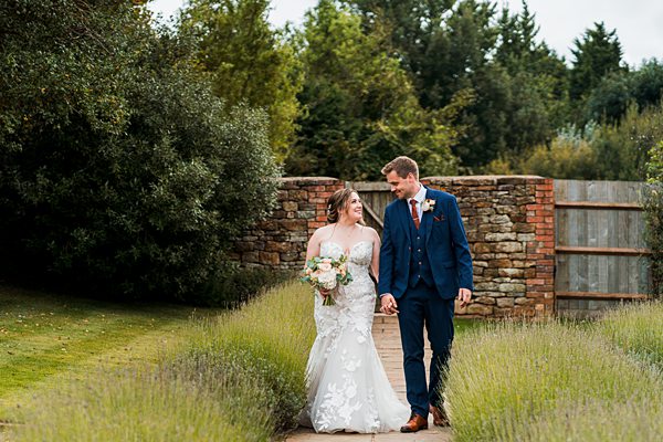 Bride and groom walking in garden path.