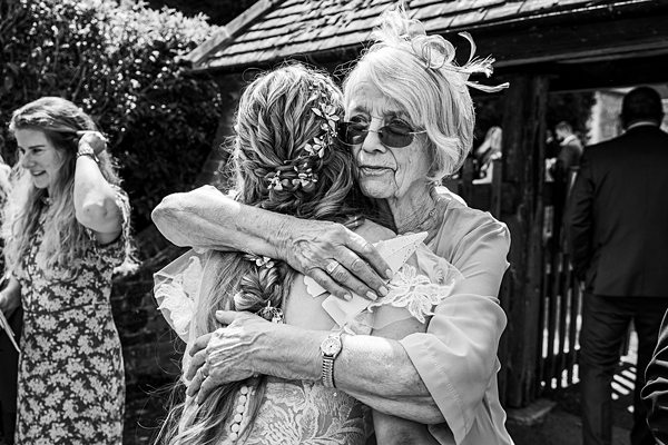 Elderly woman hugging a bride at wedding.