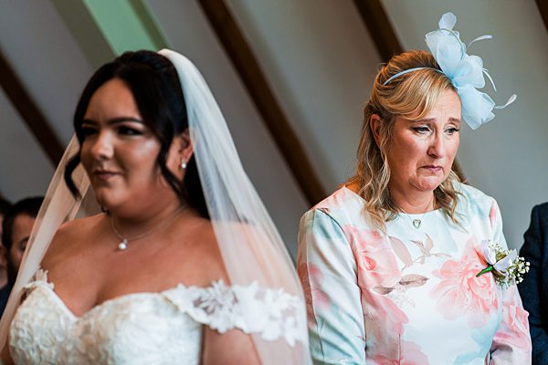 Bride and emotional woman at wedding ceremony.