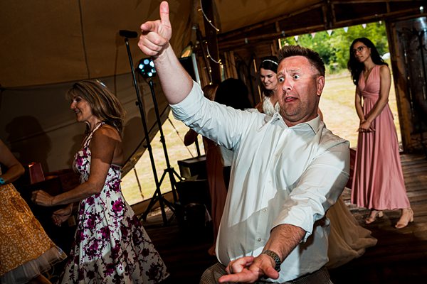 Man enthusiastically dancing at outdoor wedding.