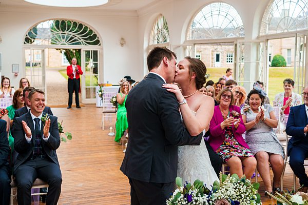 Bride and groom kissing in wedding ceremony.