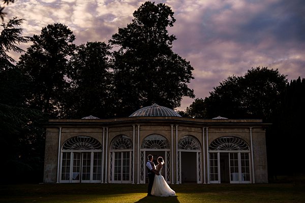 Bride and groom in front of elegant building.