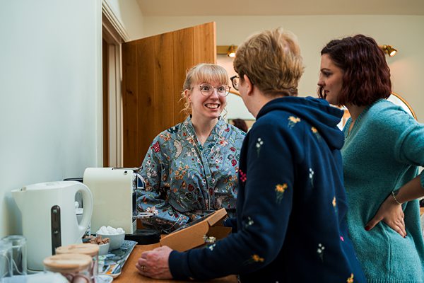 People chatting by a kettle in kitchen.