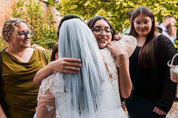 Bride hugging guests at outdoor wedding celebration.