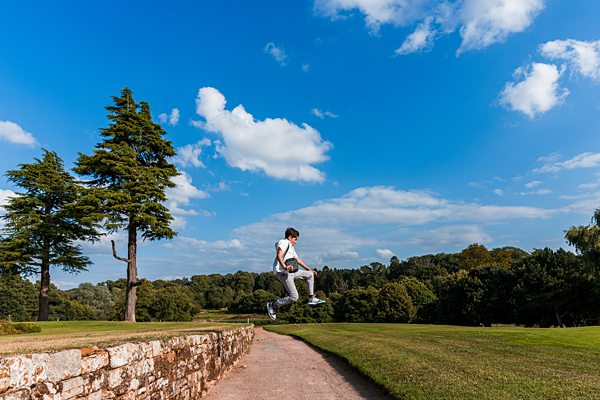 Person jumping on a path in countryside landscape.
