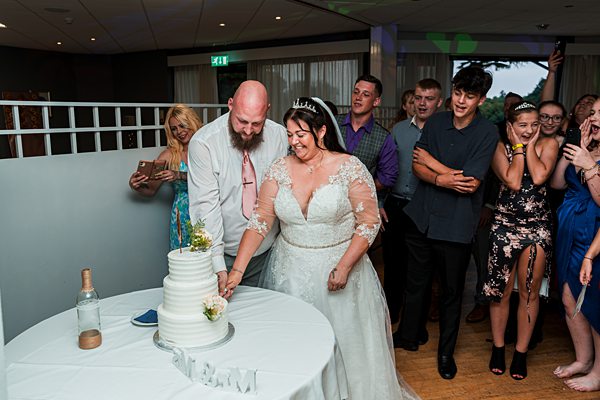 Bride and groom cutting wedding cake together.