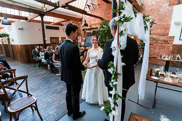 Couple exchanging vows in a rustic wedding venue.