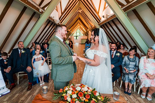 Bride and groom exchanging vows in wooden chapel.