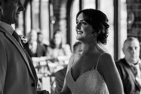 Bride smiling during wedding ceremony indoors.