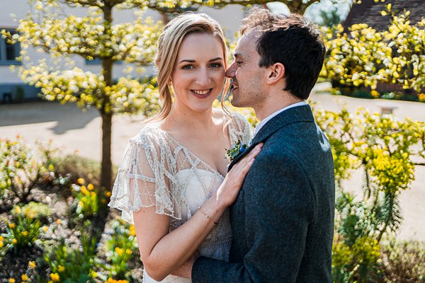 Smiling couple embraces in sunny garden.