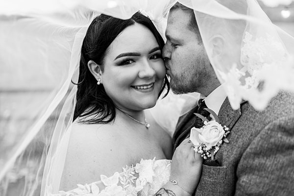 Bride and groom under veil on wedding day