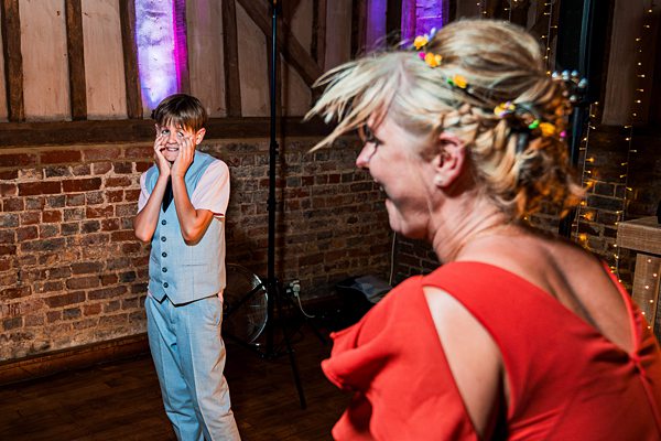 Woman and boy dancing and laughing at wedding reception.