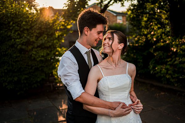 Smiling couple embraces outdoors at sunset.