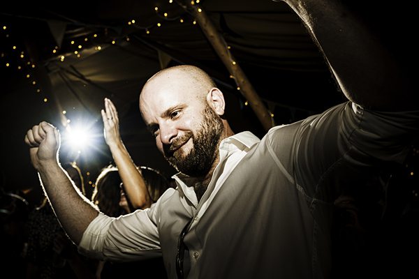 Man dancing at festive party with lights.