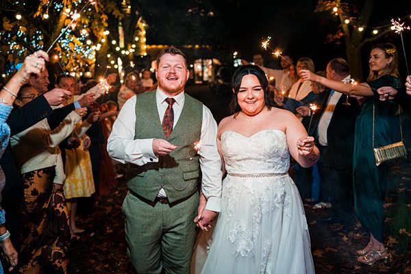 Bride and groom with sparklers at night reception.
