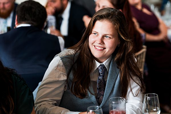 Person smiling at formal event with drinks.