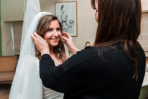 Bride smiling while adjusting her veil