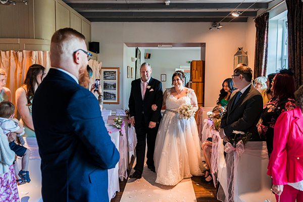 Bride walking down aisle with father at wedding.