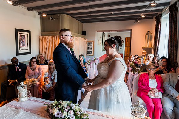 Wedding ceremony with couple holding hands, guests seated.