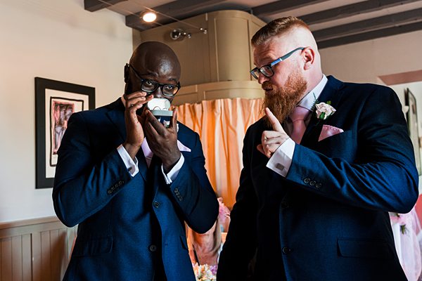 Two groomsmen in suits sharing a playful moment.