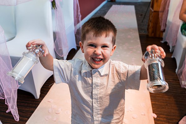Smiling child holding salt and pepper shakers indoors.