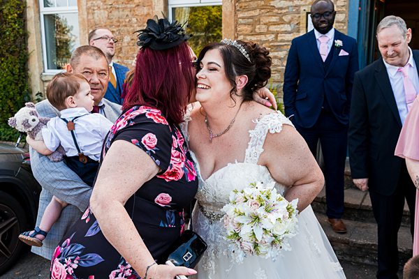 Bride hugging guest at outdoor ceremony.