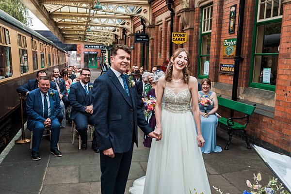 Wedding ceremony at vintage train station, smiling couple.