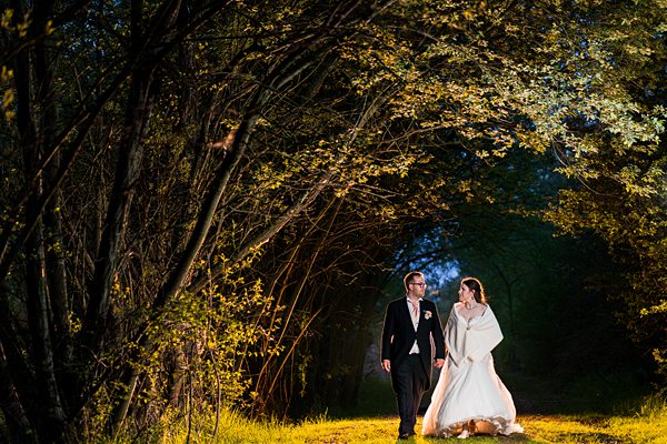 Bride and groom walking under tree archway