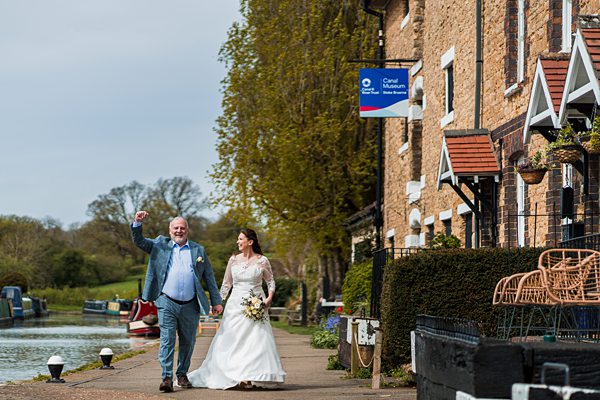 Bride and groom walking by canal museum.