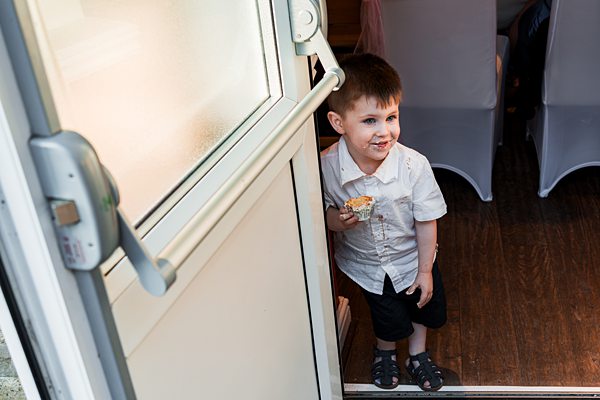 Young boy holding cupcake at doorway, smiling.