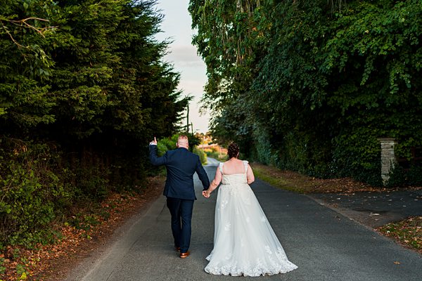 Bride and groom walking down a country road.