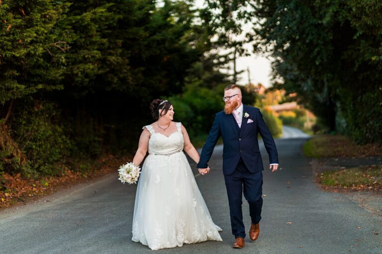 Smiling bride and groom walking hand in hand.