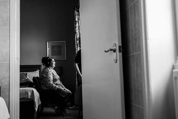 Woman in bedroom sitting, side view, black and white.