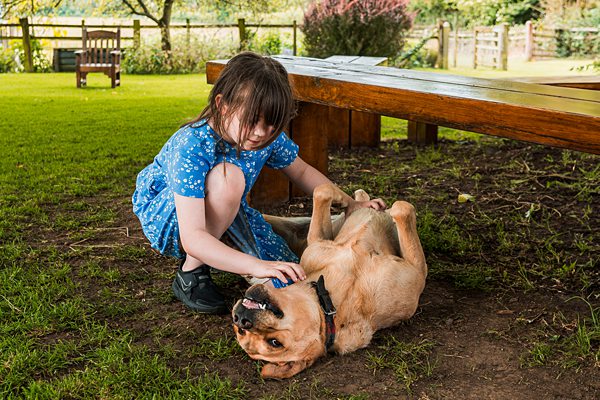 Child playing with a dog in the garden.