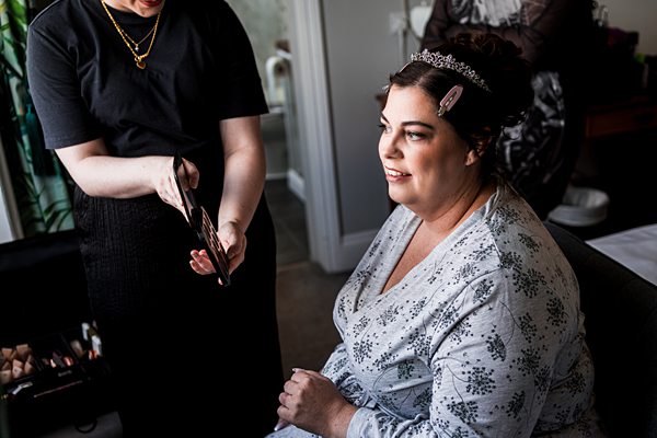 Woman getting her makeup done, smiling, wearing a tiara.