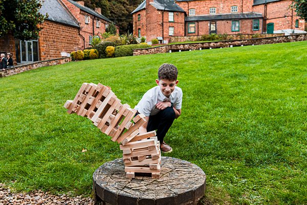 Boy playing giant Jenga on grass.