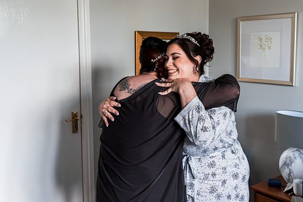 Two women hugging in a cosy room.