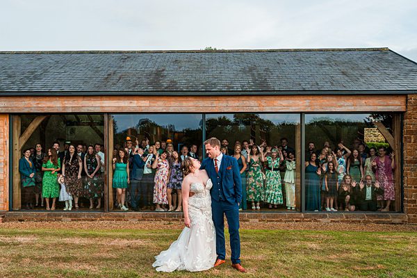 Bride and groom with guests in background at venue.